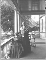 SA0004 - Emma Neale is seated on a rocking chair and Sadie Neale is standing. They are on a porch. Caption on the back., Winterthur Shaker Photograph and Post Card Collection 1851 to 1921c